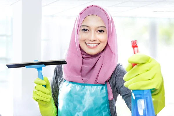 Jovem mulher limpar janelas com rodo e spray de limpeza — Fotografia de Stock