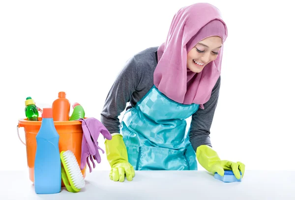 Young woman wearing hijab cleaning white table using sponge — ストック写真