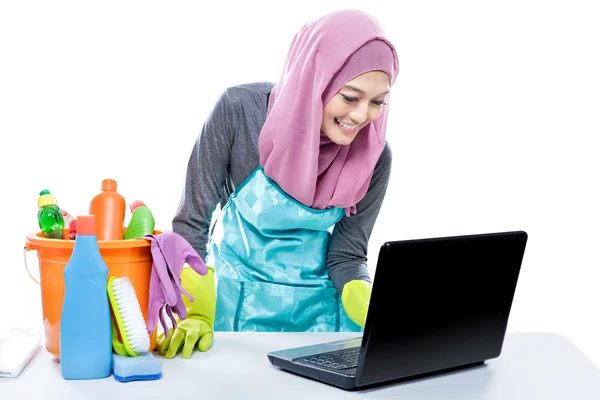 Multitasking young housewife using laptop while cleaning table — Stock Fotó