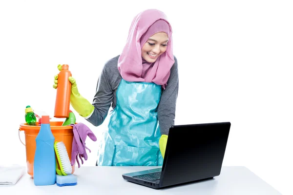 Multitasking housewife using laptop while cleaning house — ストック写真