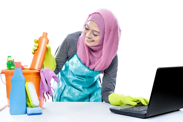 Multitasking housewife using laptop while pick up a bottle of cl — Stockfoto