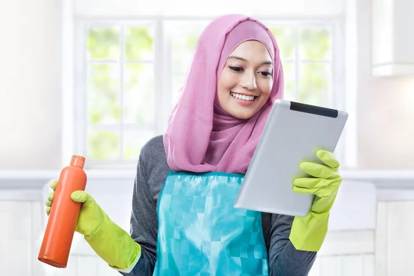 Multitâche jeune femme au foyer en utilisant la tablette tout en portant une bouteille — Photo