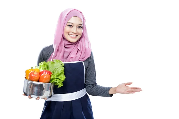 Jeune femme portant une casserole pleine de légumes et présentant flic — Photo