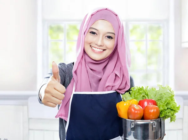 Домогосподарка, що носить сковороду з овочами і дає великі пальці вгору — стокове фото