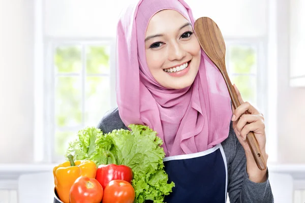 Joven mujer sonriente llevando una sartén llena de verduras y madera —  Fotos de Stock