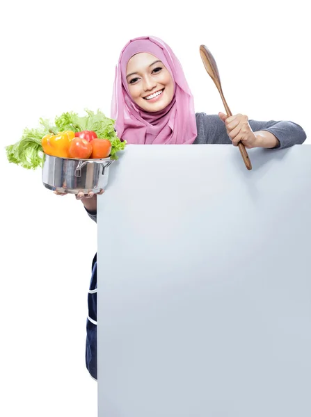 Jovem mulher sorridente carregando uma panela cheia de legumes e madeira — Fotografia de Stock