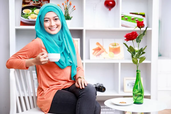 Atractiva mujer musulmana disfrutando de una taza de té en livin decorado —  Fotos de Stock