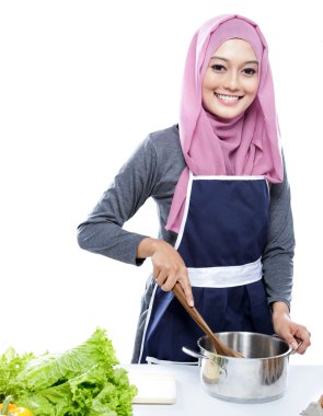 young woman wearing hijab preparing making soup for dinner