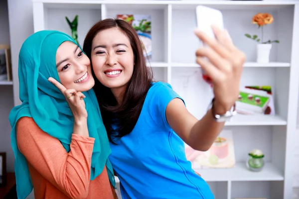 Twee vrolijke vrouwen nemen van foto's met behulp van smartphone camera — Stockfoto