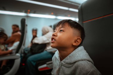 Genç bir çocuk yukarı bakıyor, derin büyülenmiş ve büyülenmiş bir uçuş yolculuğu boyunca.