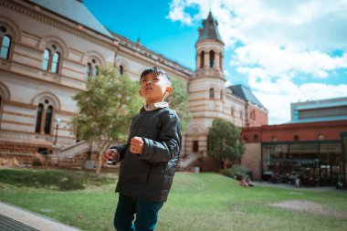 Mutlu bir çocuk güzel mimarisi olan bir parkta harika bir günün tadını çıkarır.