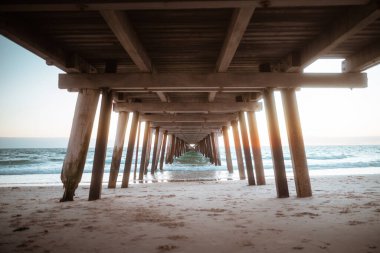 Okyanus iskelesi, gün doğumu manzaralı, sakin gündoğumu sahnesi, iskelenin altında, okyanus ve gölgelerle.