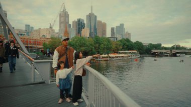 Neşeli bir aile, canlı rıhtım bölgesini keşfederken Melbourne 'da güzel bir günün tadını çıkarıyor.