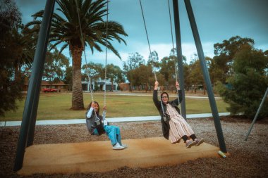 İki arkadaş güneşli park gününün keyfini çıkarırken, iki arkadaş palmiye altında sallanan neşeli anı paylaşıyor.