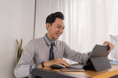 Sanal toplantı sırasında Asyalı erkek sunucu jestleri, profesyonel gömlekli özgüvenli ifade, kitaplık arkaplanı