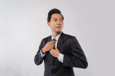 Asyalı CEO kravatı ayarlıyor ve kamera dışında görünüyor, düşünceli yönetici portresi vizyon ifadesi, terzi ceketi, yumuşak