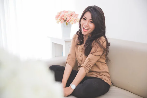 Cheerful woman sitting on a couch — Stock Photo, Image