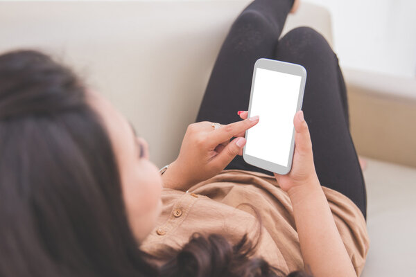 Woman laying on a couch, holding a cellphone.