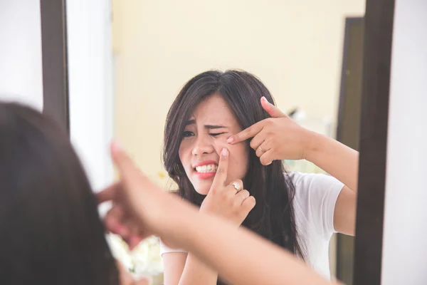 Mujer apretando espinillas mirar al espejo — Foto de Stock