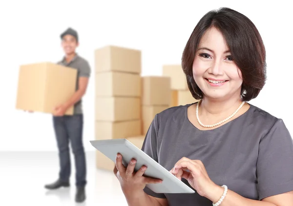 Woman holding tablet pc, courier and boxes in the background — Stock Photo, Image