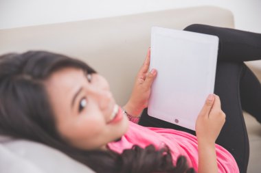 Tablet PC'yi kullanma bir kanepede döşenmesi kadın
