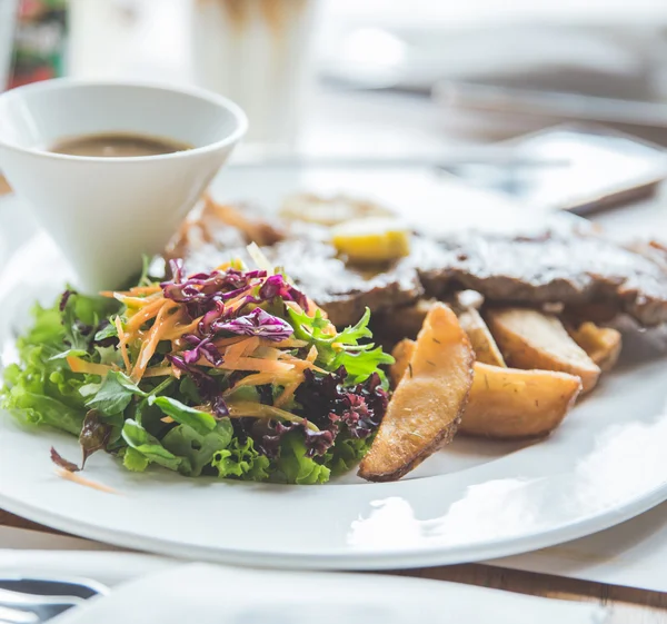 Bife grelhado com salada e fatias fritas batata — Fotografia de Stock