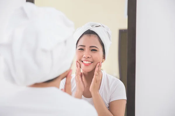 Mulher aplicando loção skincare em seu rosto — Fotografia de Stock