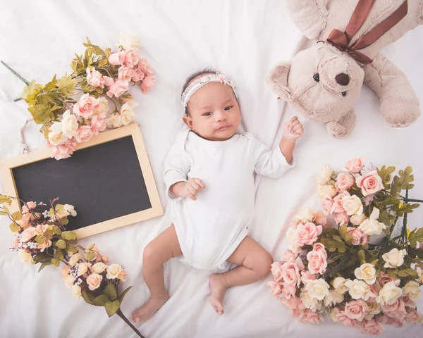 Mignon asiatique bébé fille sur couverture blanche à côté de tableau blanc , — Photo
