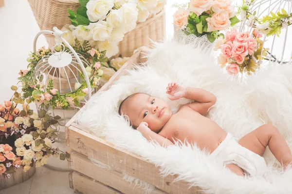 Asiatique bébé fille dans une boîte avec couverture blanche, fleurs à haute voix — Photo