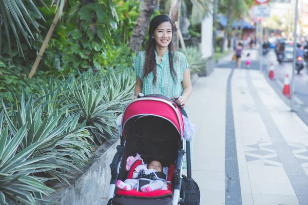 Žena se projít s dítětem uvnitř baby kočárek — Stock fotografie