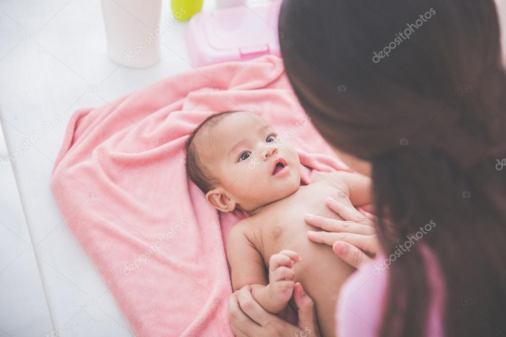woman applying baby lotion to her baby