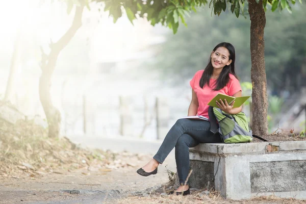 Mladá asijská studentka sedí venku, čtení knihy — Stock fotografie