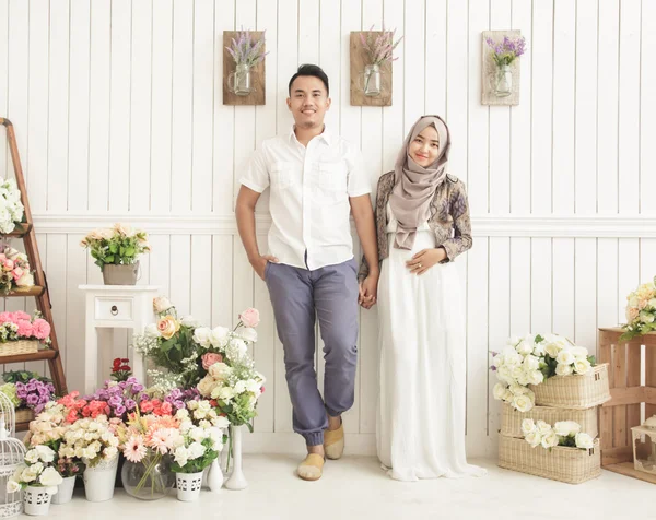 Супружеская пара, стоящая и улыбающаяся в украшенной комнате — стоковое фото