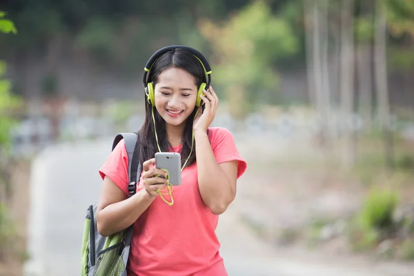 年轻的亚洲学生在她的户外活动，听木 — 图库照片