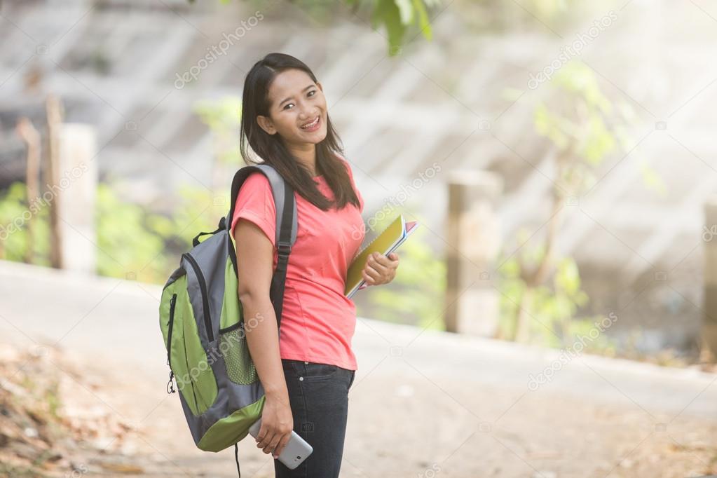 Young Asian student in her outdoor activity, standing and tiltin