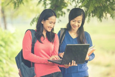 İki genç Asyalı öğrenciler birlikte, bir dizüstü bilgisayar holding ayakta