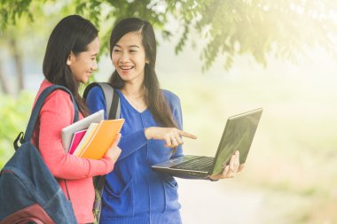 İki genç Asyalı öğrenciler birlikte, bir dizüstü bilgisayar holding ayakta