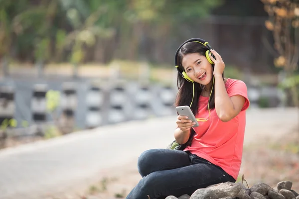 Mahasiswa muda Asia dalam aktifitas luarnya, mengenakan headset a — Stok Foto