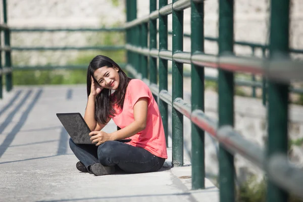 Joven estudiante asiático sentado al aire libre, utilizando un ordenador portátil — Foto de Stock