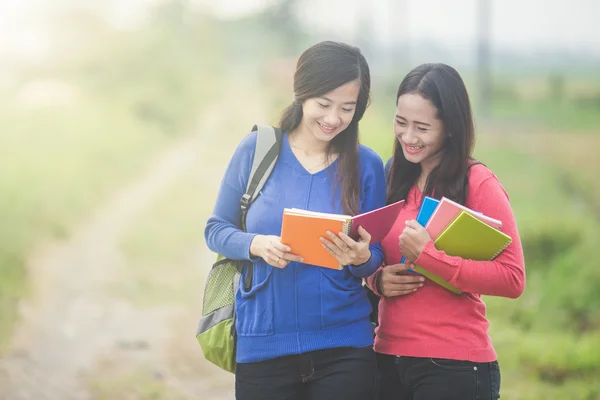 Two young Asian students reading something on the book — Stock Photo, Image