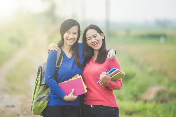 Deux jeunes étudiants asiatiques tenant des livres, souriant vivement à la — Photo