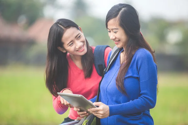 Два молодых азиатских студента с помощью планшетного компьютера — стоковое фото