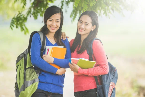 Due giovani studenti asiatici che tengono libri, sorridendo brillantemente al — Foto Stock