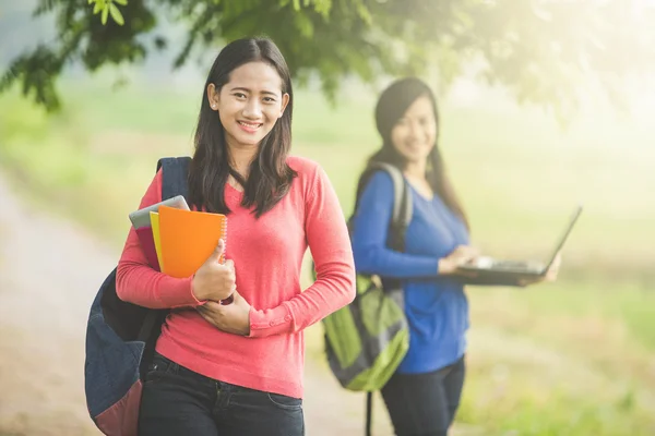 亚洲学生和她的朋友站在背景握着 — 图库照片