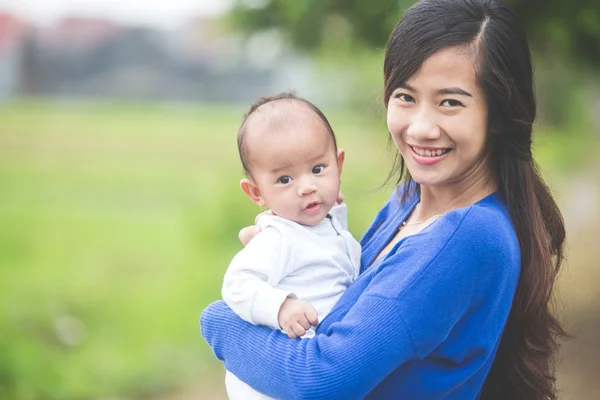 Hermosa asiático madre holding su bebé hija — Foto de Stock