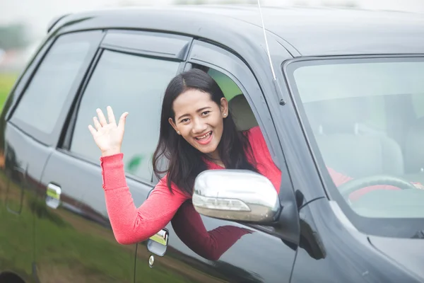 Młode azjatyckie kobiety podczas prowadzenia samochodu, machając jej rękę z wiatrem — Zdjęcie stockowe