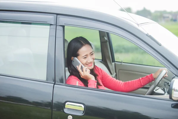 Young Asian woman talking on the phone while driving a car — Stock Photo, Image