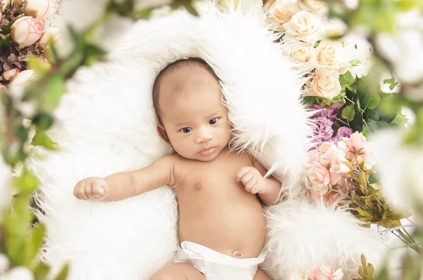 Schattig klein babymeisje op bont deken met bloemen — Stockfoto