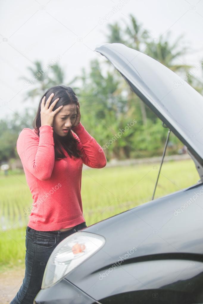 Young Asian woman holding her head, confuse because her car trou