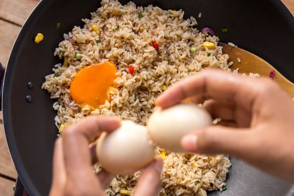 Людські руки розтріскують яйце для додавання в смажений рис — стокове фото